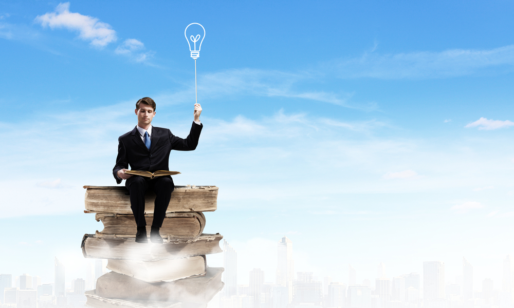 Young businessman sitting on pile of books